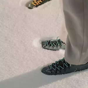 Zwei Paar Füße in Wanderschuhen stehen im frischen, knöchelhohen Schnee