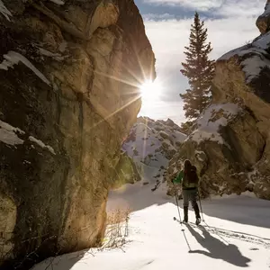 Skitouren-Wanderin im Tiefschnee mit untergehender Sonne