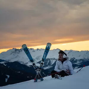 Skifahrerin in der Abenddämmerung bei einer Rast mitten im Tiefschnee