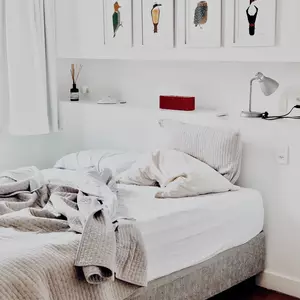 Doppelbett mit Überwurf und Bilderregal über dem Kopfteil