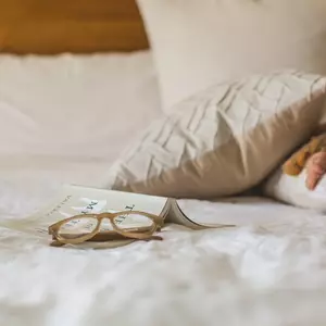 Detailaufnahme Doppelbett mit Kissen, Buch und Lesebrille